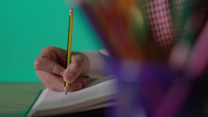 رجل سعودي يكتب في دفتر خلفية خضراء