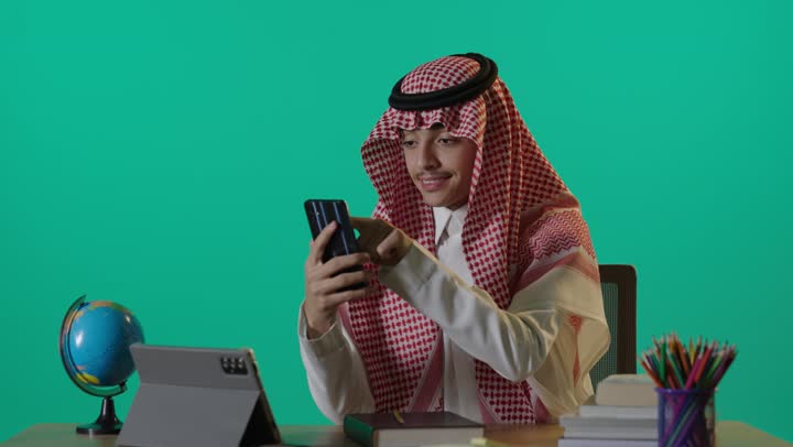Saudi Student Using Smartphone at Desk Green Screen