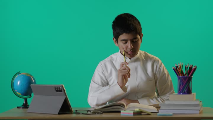 طالب سعودي يكتب في كتاب أمام خلفية كروما