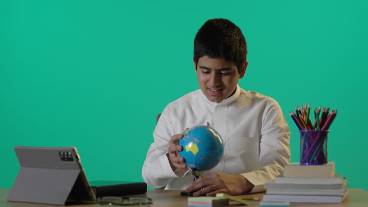 Saudi Boy in White Thobe Studying Globe Green Screen