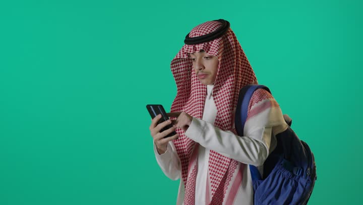طالب سعودي يستخدم هاتف ذكي خلفية خضراء