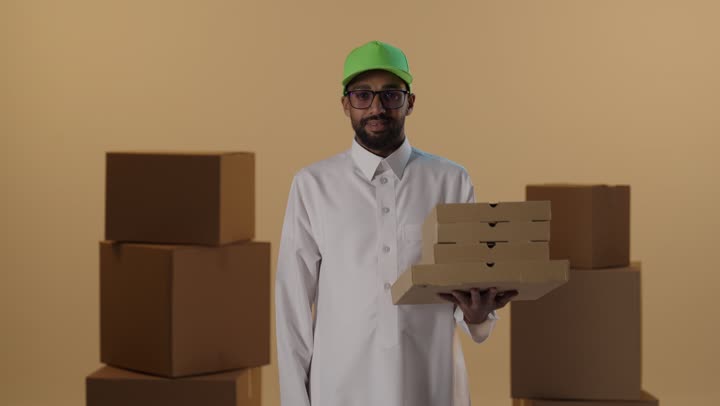 رجل توصيل عربي يحمل صناديق بيتزا مع إشارة الإبهام