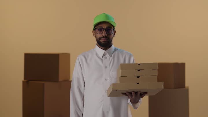 رجل توصيل سعودي يشير بعدم الرضا مع صناديق بيتزا