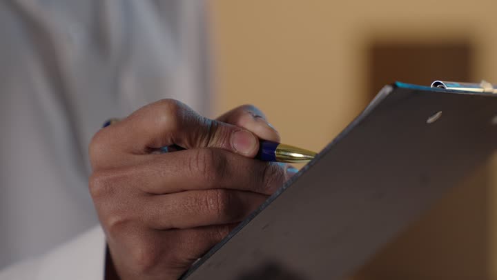 يد طبيب تكتب على لوحة الملاحظات لقطة مقربة