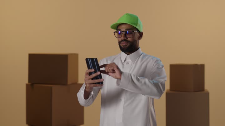 رجل توصيل سعودي يستخدم الهاتف الذكي في المستودع