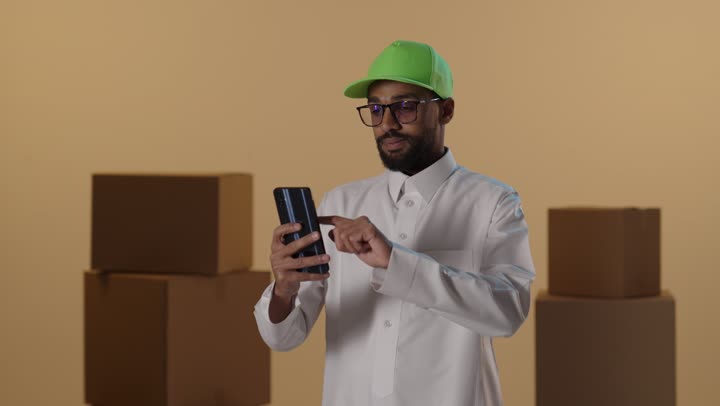 رجل توصيل سعودي يستخدم الهاتف بين الصناديق