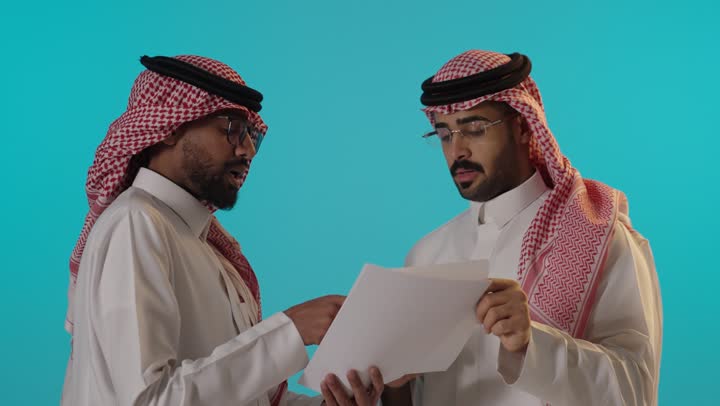 رجال سعوديون يناقشون مستندات عمل في الاستوديو