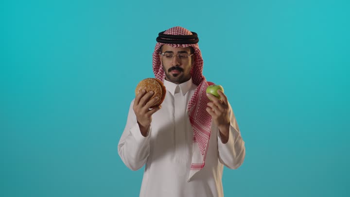 Saudi Man Choosing Between Burger and Green Apple