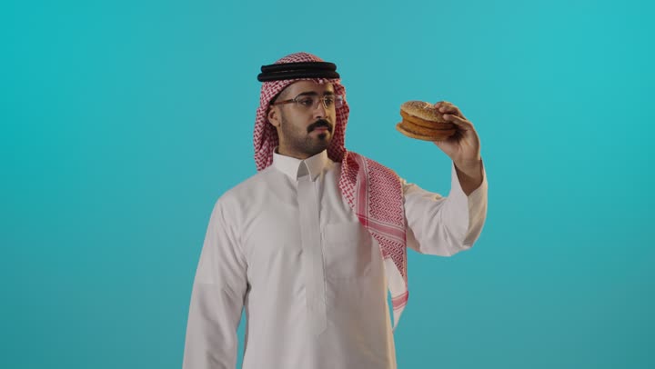 رجل سعودي يحمل برجر مع إيماءة الإبهام للأعلى