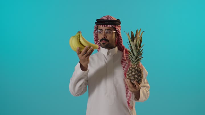 رجل سعودي يمسك بالموز والأناناس في الاستوديو