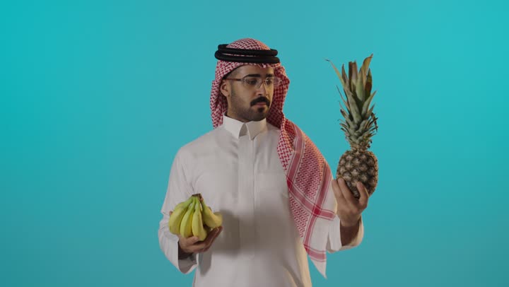 Saudi Man Holding Pineapple and Bananas Studio Footage