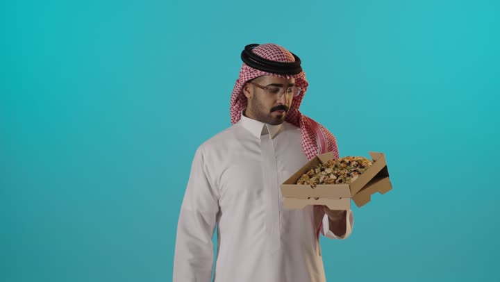رجل سعودي يمسك صندوق بيتزا في الاستوديو