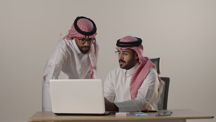 Saudi Businessmen Discussing Data on Laptop in Office