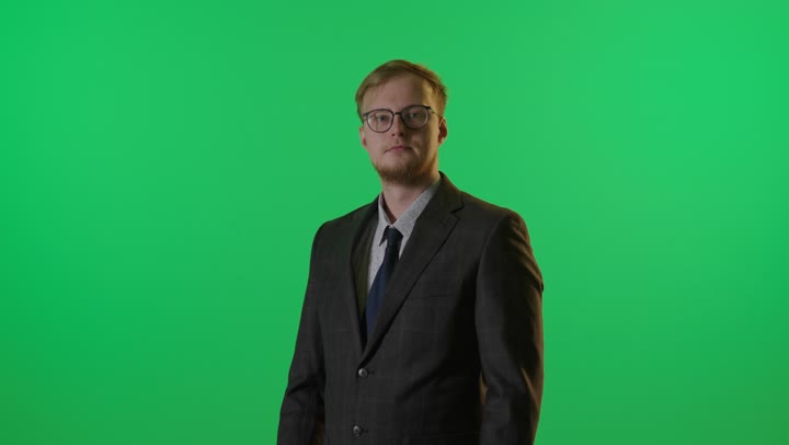 رجل أعمال يقف أمام خلفية خضراء مكتف اليدين