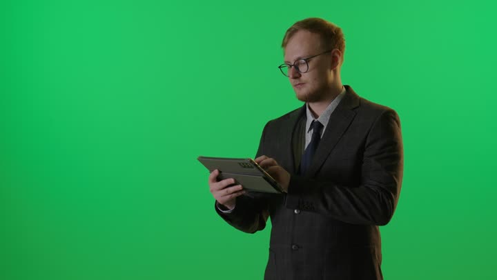 رجل أعمال متفاجئ يستخدم جهاز لوحي أمام الكروما