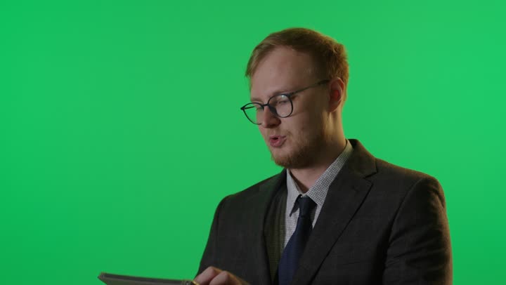 رجل أعمال يستخدم جهاز لوحي أمام شاشة خضراء