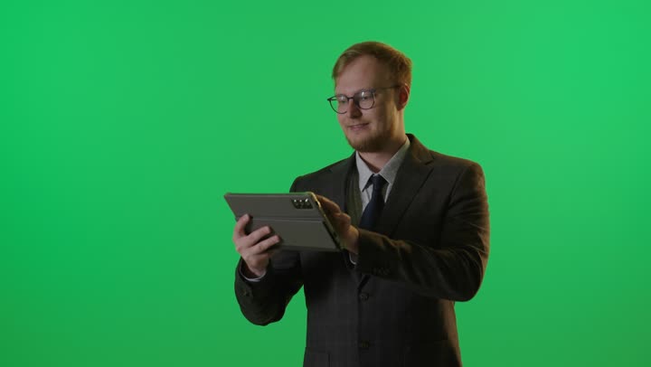 رجل أعمال يستخدم جهاز لوحي أمام الكروما الخضراء