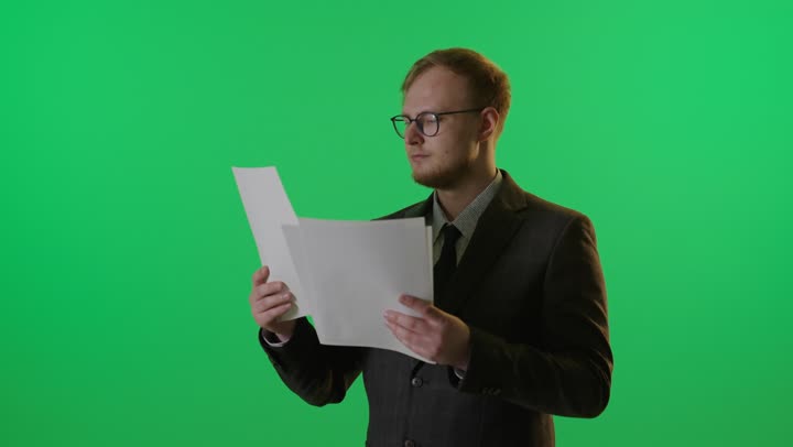 رجل أعمال يقرأ مستندات أمام كروما خضراء