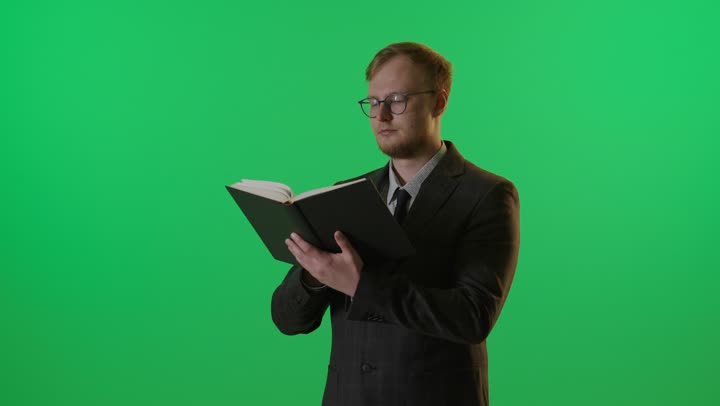 رجل يقرأ كتاباً على خلفية شاشة خضراء