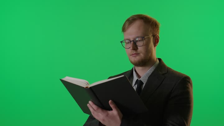 رجل يقرأ كتاباً أمام خلفية شاشة خضراء