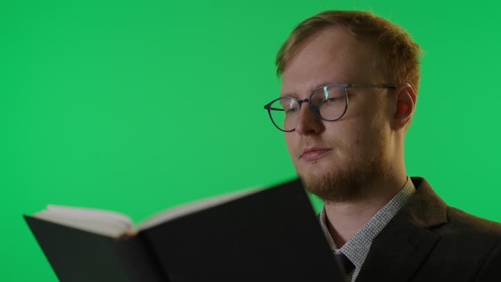 رجل أجنبي يقرأ كتاباً أمام خلفية كروما خضراء