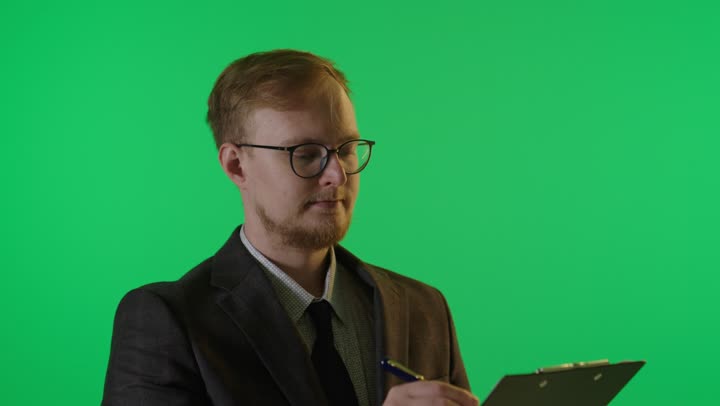 رجل أعمال يكتب على لوحة ملاحظات خلفية خضراء