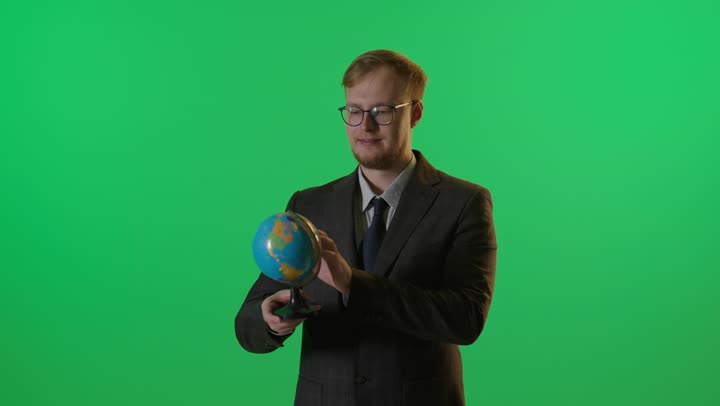 رجل أعمال يدور مجسم الكرة الأرضية خلفية خضراء
