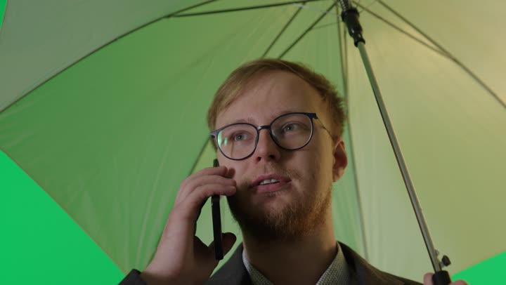 رجل أعمال يتحدث بالهاتف مع مظلة كروما خضراء