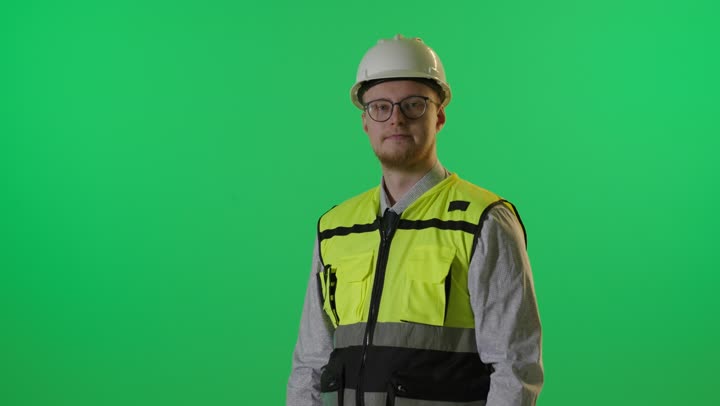 مهندس يقف أمام خلفية كروما خضراء بطي الذراعين