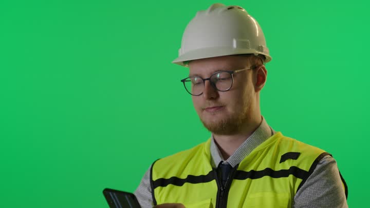Engineer in Safety Gear Using Smartphone on Green Screen