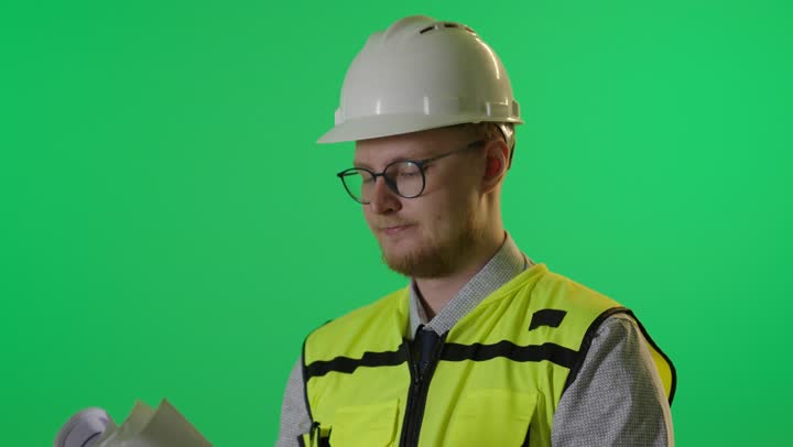مهندس معماري يتفحص مخططات هندسية على خلفية خضراء