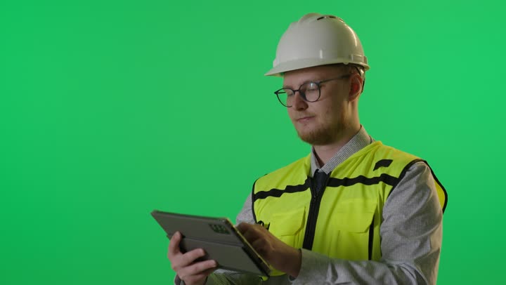 مهندس أجنبي يستخدم جهاز لوحي أمام خلفية خضراء