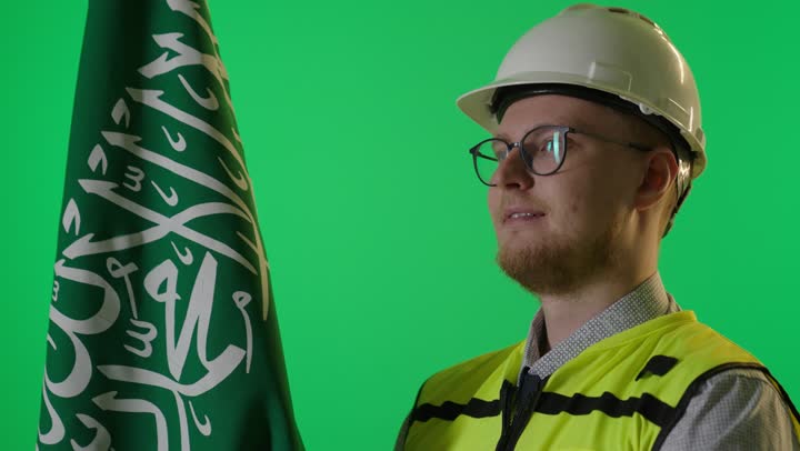 مهندس مع علم السعودية أمام خلفية خضراء