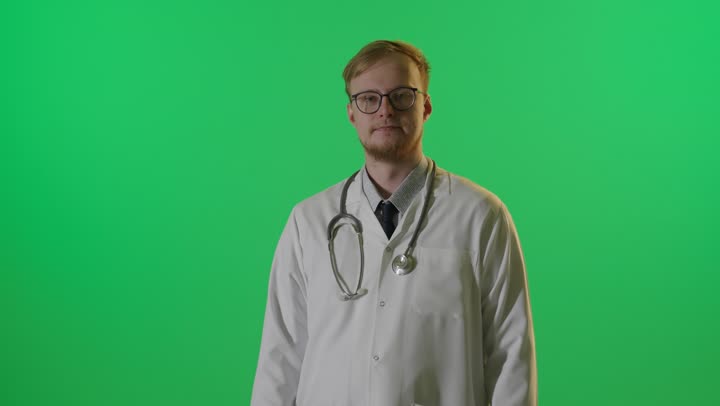 طبيب ذكر أمام كروما خضراء بوضعية واثقة