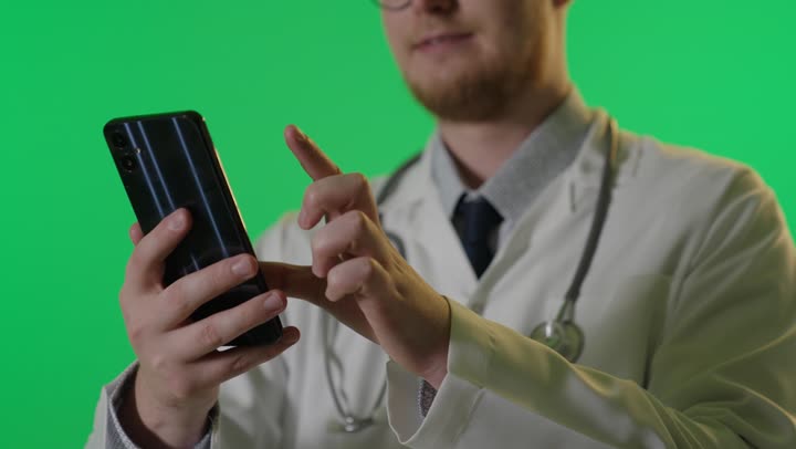 طبيب يستخدم الهاتف الذكي أمام خلفية خضراء