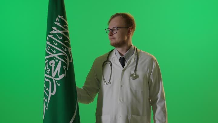طبيب يقف بجانب العلم السعودي كروما خضراء