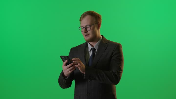 رجل أعمال يستخدم الهاتف الذكي أمام شاشة خضراء