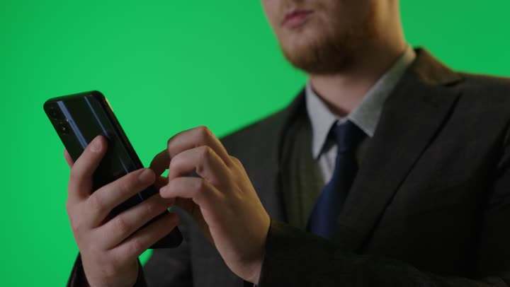 رجل أعمال يستخدم الهاتف الذكي بخلفية كروما خضراء