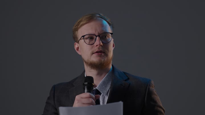 رجل في بدلة رسمية يلقي خطاباً مع ميكروفون