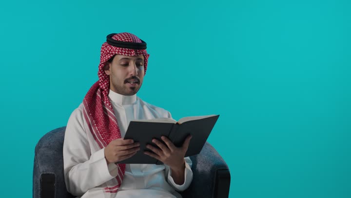 Saudi Man in Traditional Thobe Reading Book in Studio