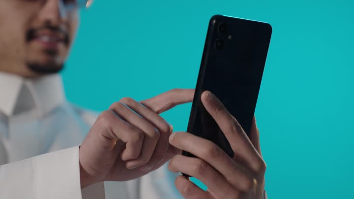 Saudi Man Using Smartphone on Blue Background