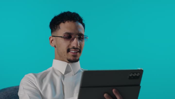 شاب سعودي يستخدم جهاز لوحي بخلفية زرقاء