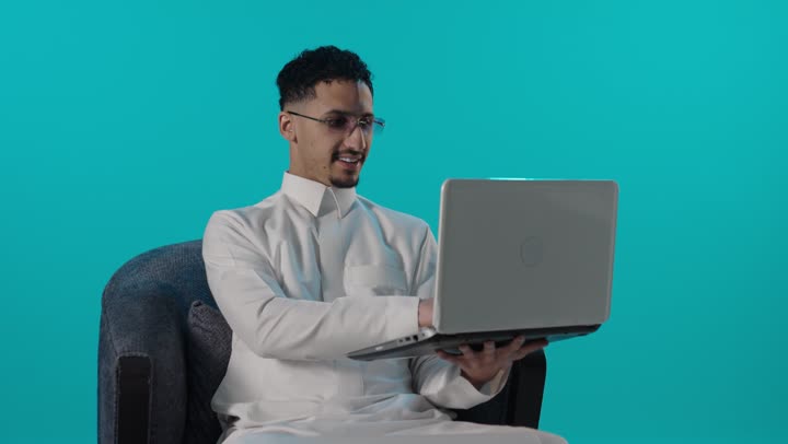 Saudi Man Working on Laptop Blue Background Video