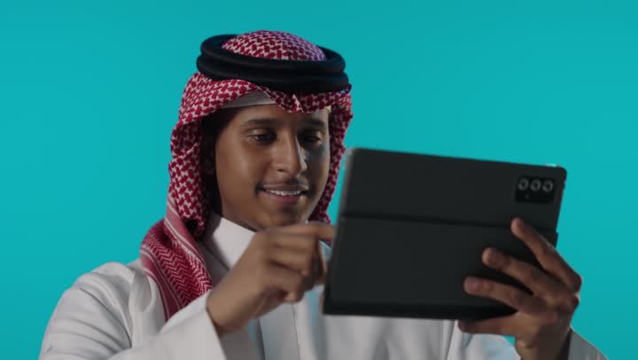 Saudi Man Using Tablet on Blue Background