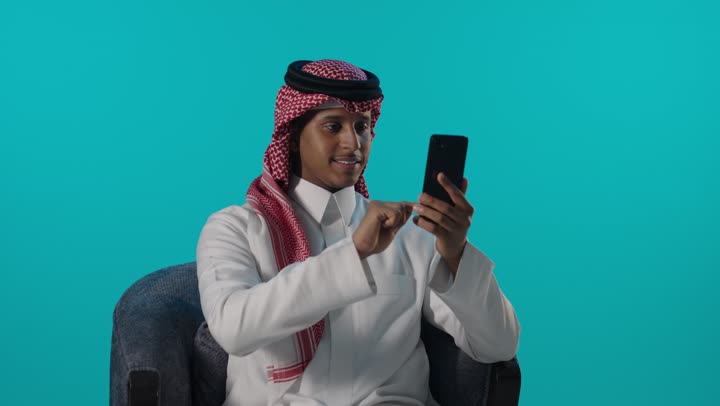 Saudi Man Using Smartphone on Blue Background Studio