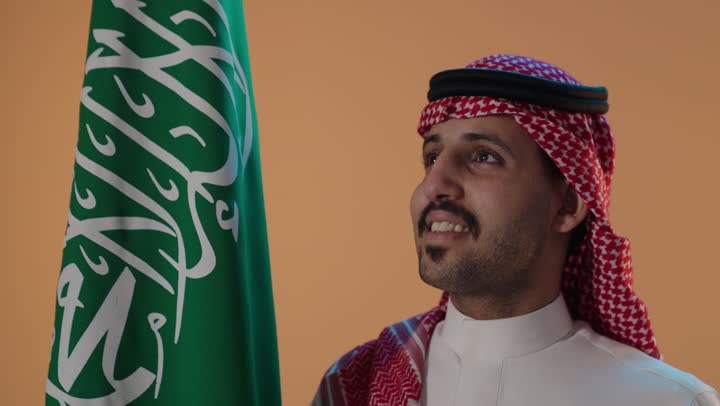 Saudi Man Smiling Next to Saudi Flag Portrait