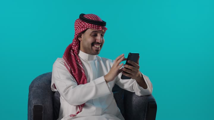 رجل سعودي يستخدم الهاتف الذكي بخلفية فيروزية