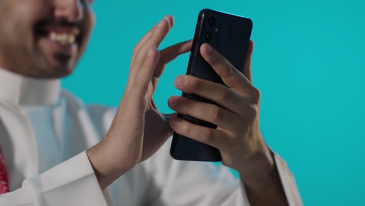 رجل سعودي يستخدم الهاتف الذكي بخلفية فيروزية