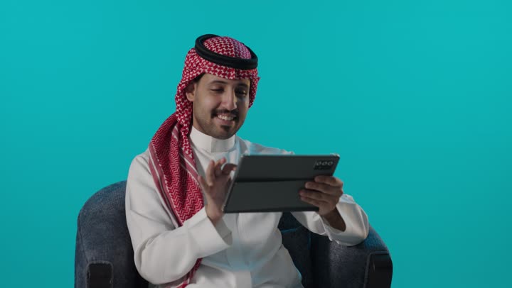 رجل سعودي يستخدم جهاز لوحي على خلفية زرقاء