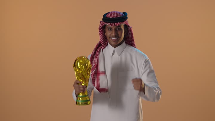 رجل سعودي يحتفل بكأس كرة القدم في الاستوديو